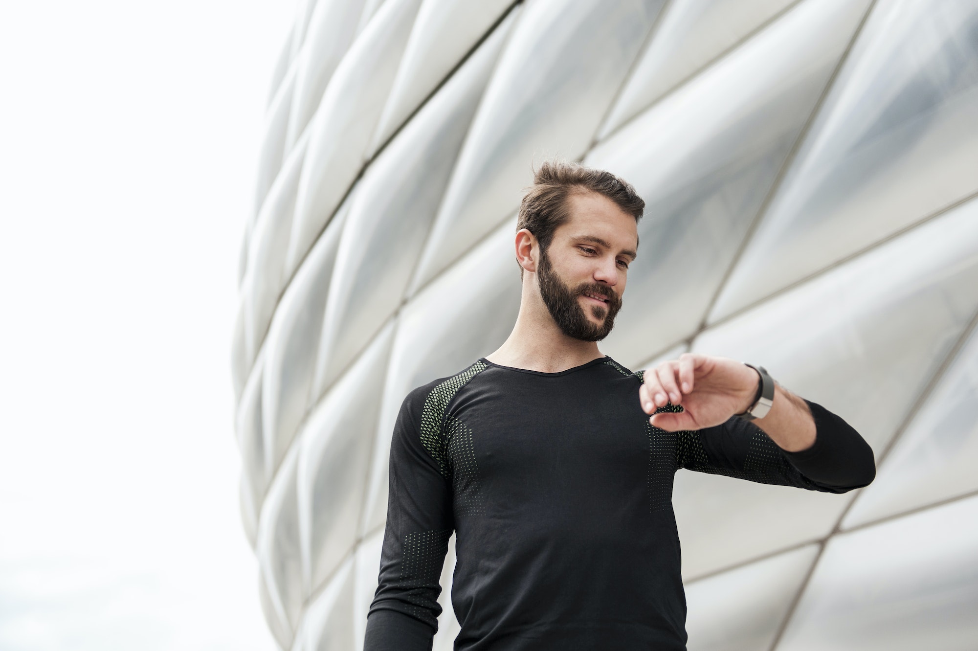 Smiling athlete checking the time at stadium